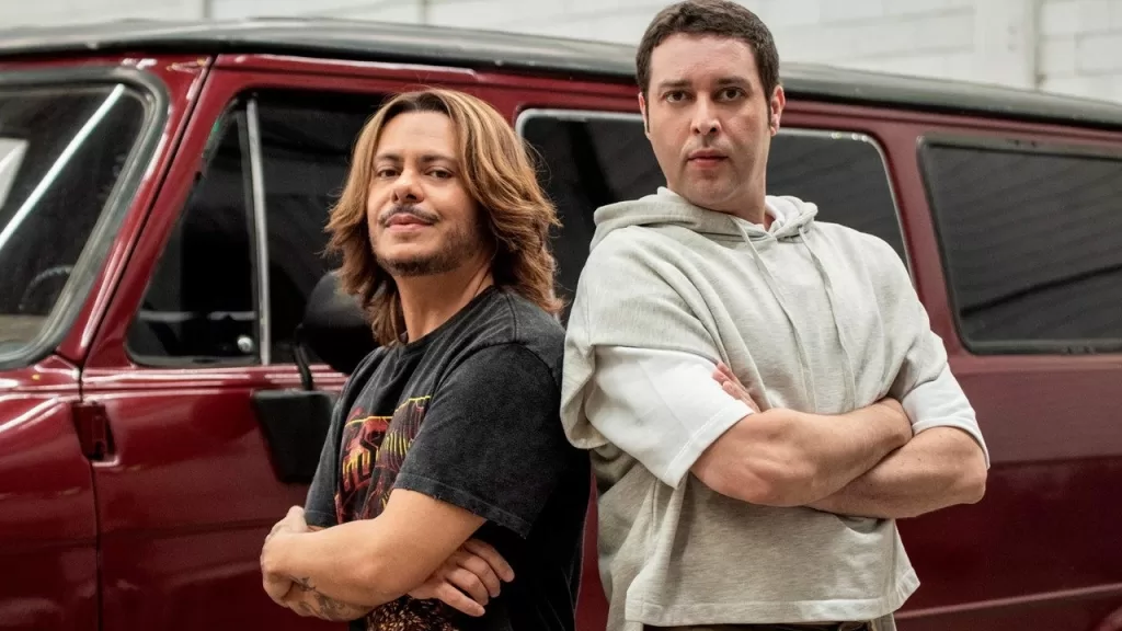 Marcus Majella e Pedroca Monteiro, os protagonistas de Agentes Muito Especiais, posam lado a lado diante de um carro vermelho