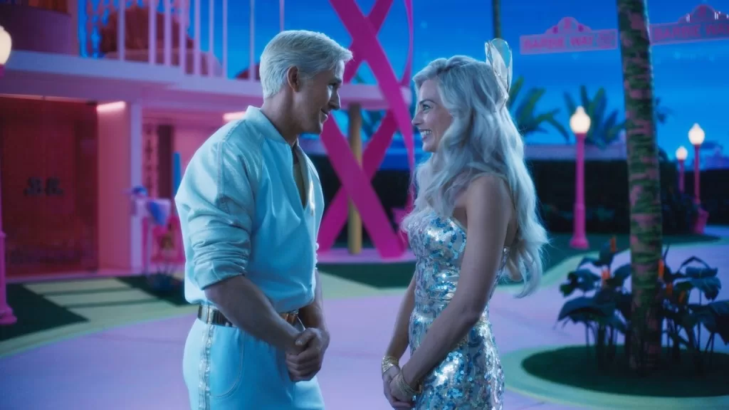Margot Robbie como Barbie e Ryan Gosling como Ken, de mãos dadas em uma rua cor-de-rosa da Barbieland, em cena de Barbie (2023)