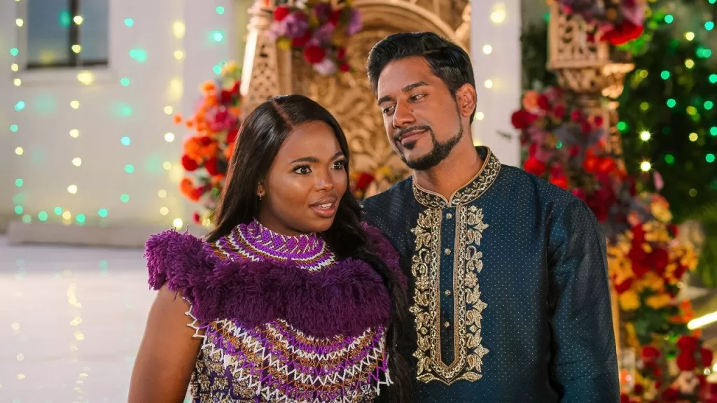 Casal protagonista de Como Acabar com o Diwali com roupas tradicionais em uma festa decorada com flores e luzes