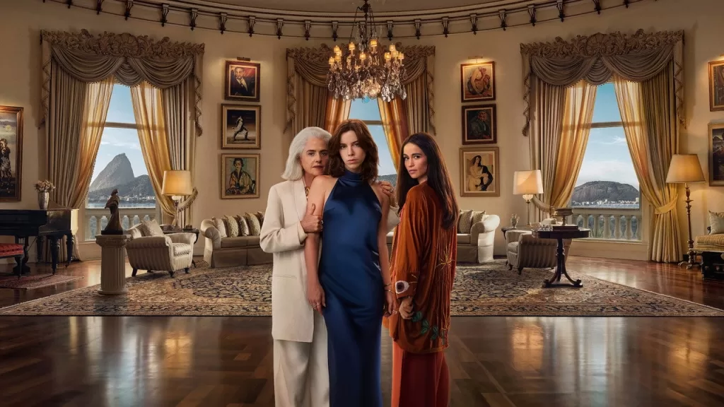 Marieta Severo, Alice Wegmann e Nanda Costta em pé em uma sala luxuosa de mansão com vista para o Rio de Janeiro, em cena da série Dom de Iludir