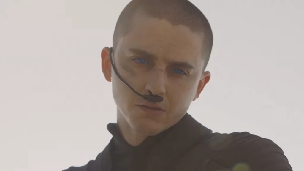 Timothée Chalamet como Paul Atreides, de cabelo raspado e traje do deserto, em cena de Duna: Parte Três
