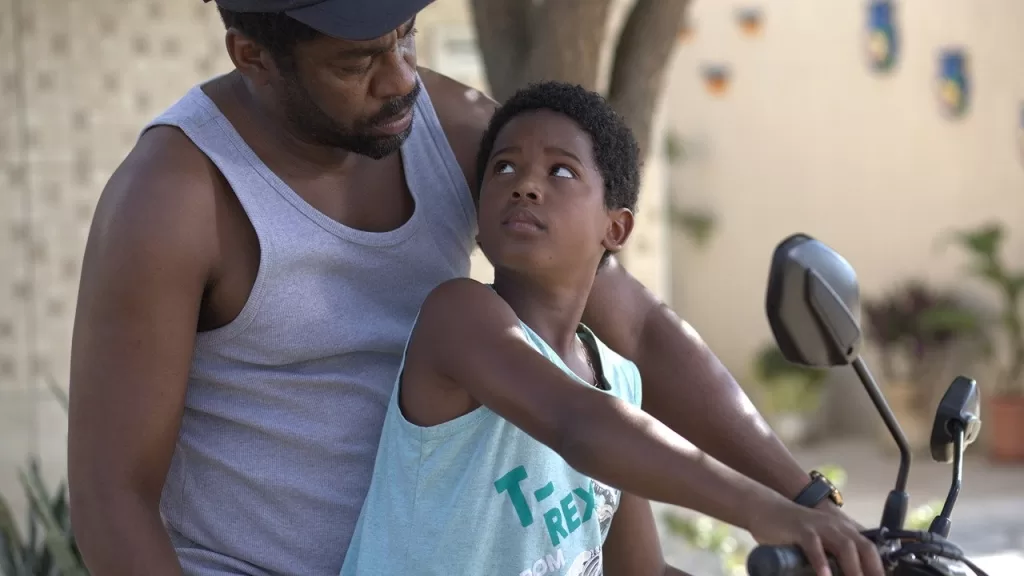 Lázaro Ramos, como Batista, pilota uma moto com o menino Gugu, vivido por Yuri Gomes, na garupa em cena de Feito Pipa