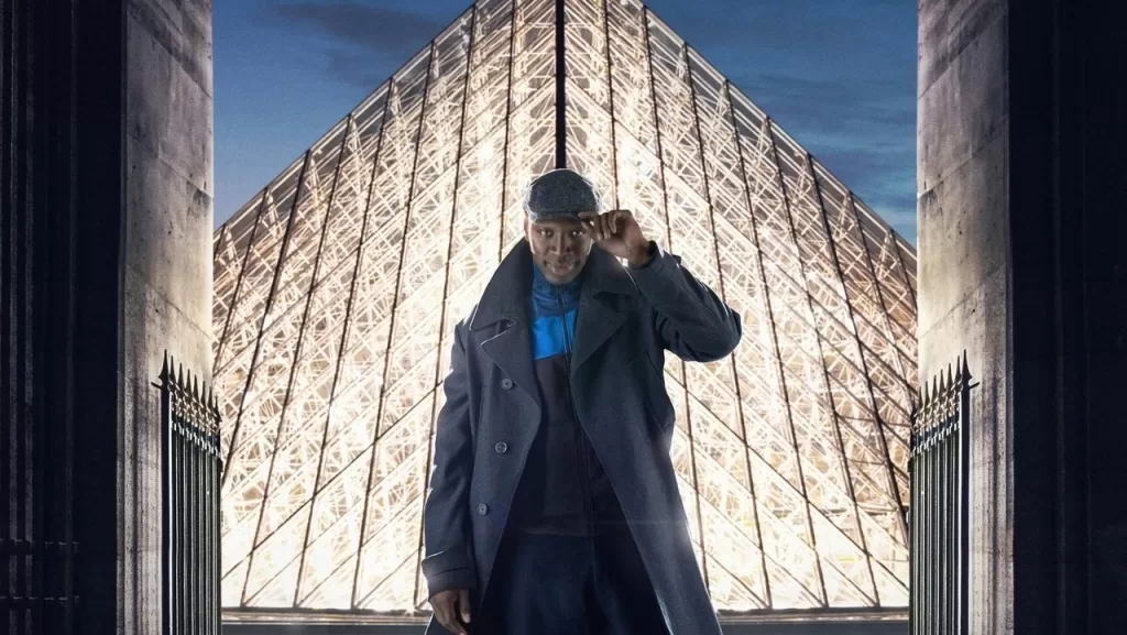 Omar Sy como Assane Diop, de sobretudo, diante da pirâmide de vidro do Museu do Louvre em cena de Lupin