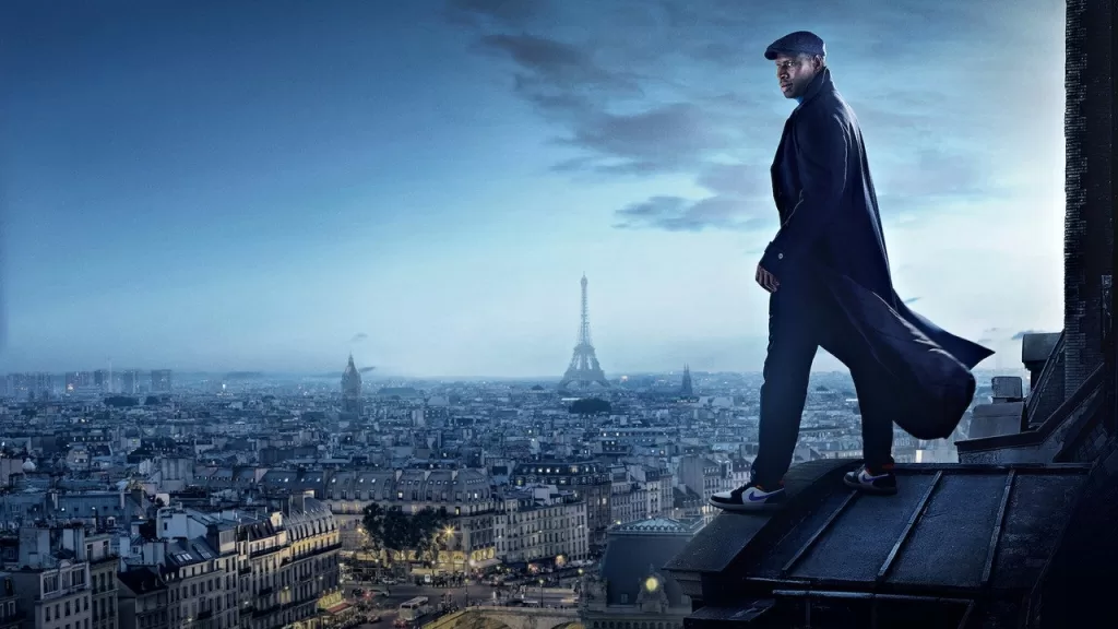 Omar Sy como Assane Diop, de sobretudo escuro, no alto de um telhado com Paris e a Torre Eiffel ao fundo