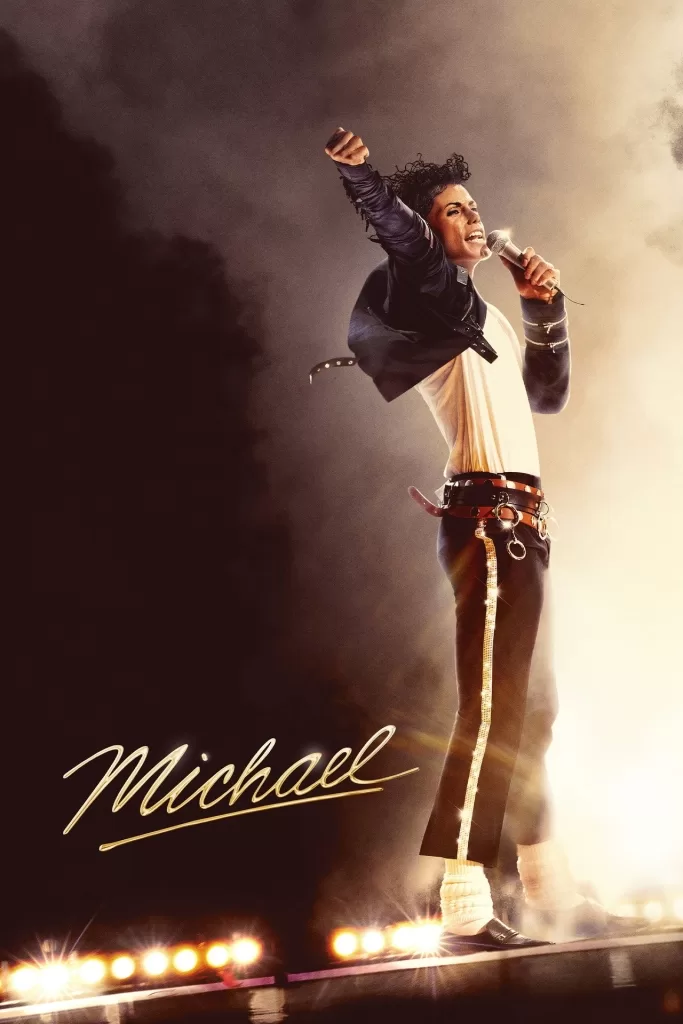 Jaafar Jackson, como Michael Jackson, de jaqueta vermelha e óculos escuros, sob luzes de palco no filme Michael