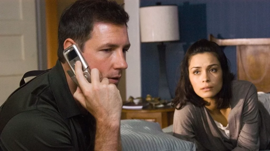 Edward Burns fala ao celular enquanto Shannyn Sossamon observa, preocupada, ao fundo