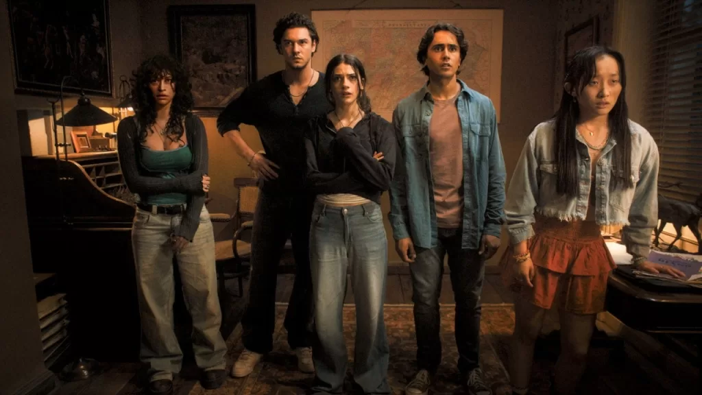 Grupo de jovens amigos reunidos dentro de uma casa escura em cena do filme Until Dawn: Noite de Terror